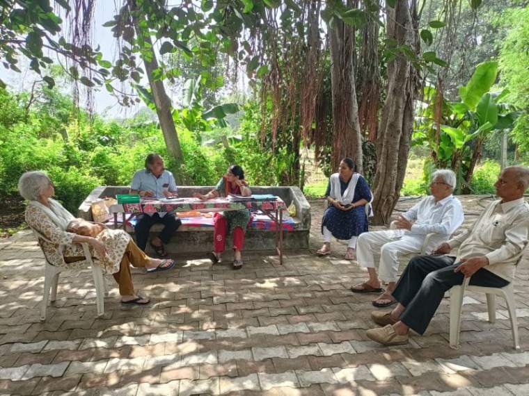 Volunteers and community members gathered under trees at a wellness camp in Dakor